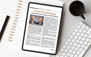 Tablet shows a magazine-style life sciences article titled 'Facet Life Sciences' on a white desk beside a spiral notebook, ruler, keyboard and coffee mug.