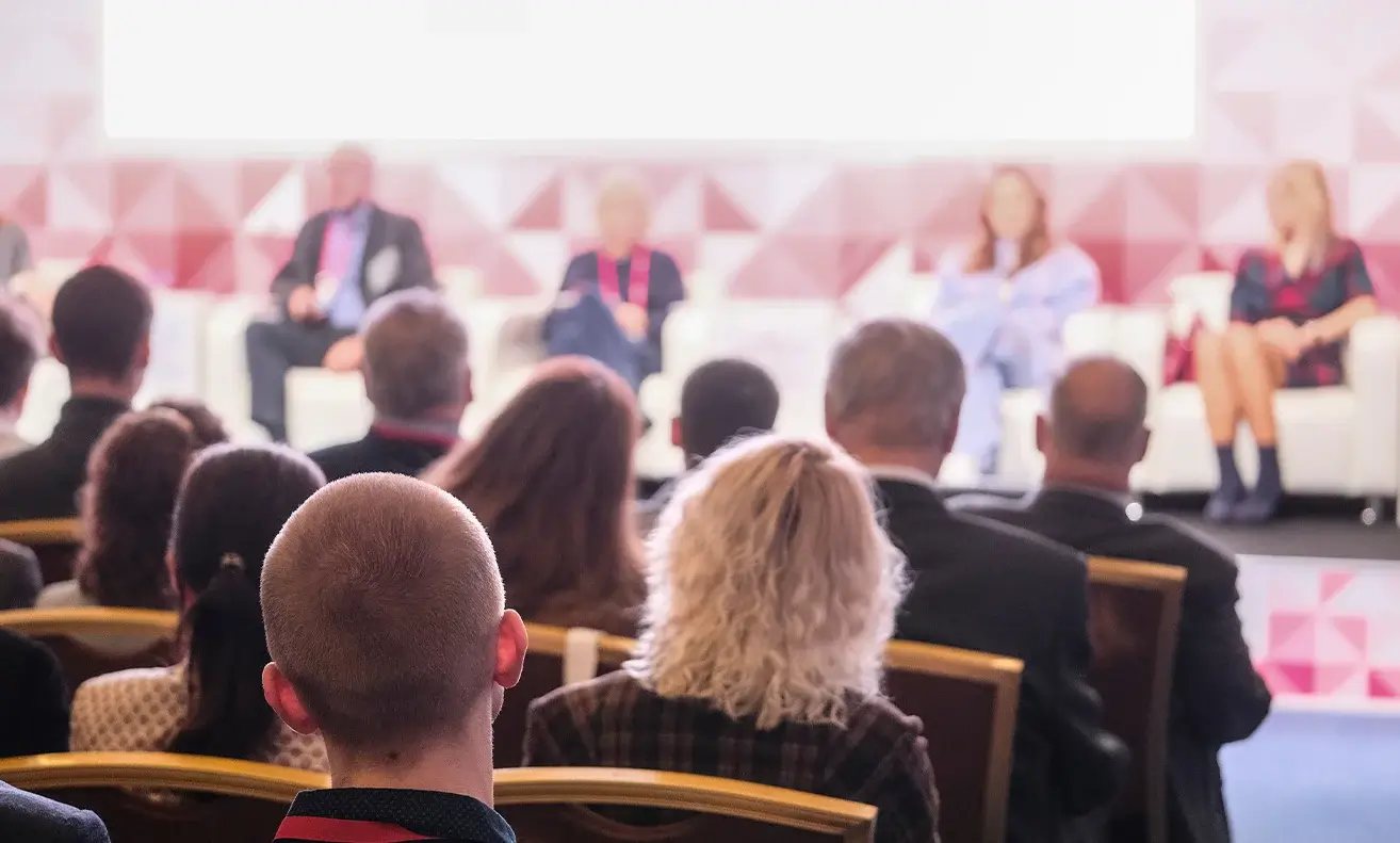 Audience watching a panel discussion on stage at a conference.
