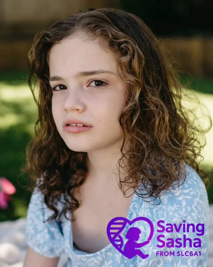 Portrait of a young girl with curly brown hair outdoors, with a purple 'Saving Sasha from SLC6A1' logo in the bottom right corner.